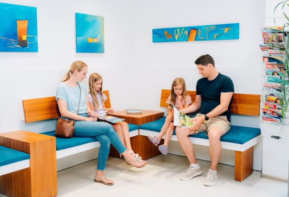 Familie mit zwei Mädchen sitzt im Wartezimmer