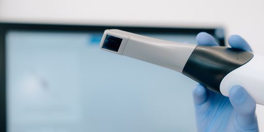 Hand in blauem Handschuh hält Intraoralscanner